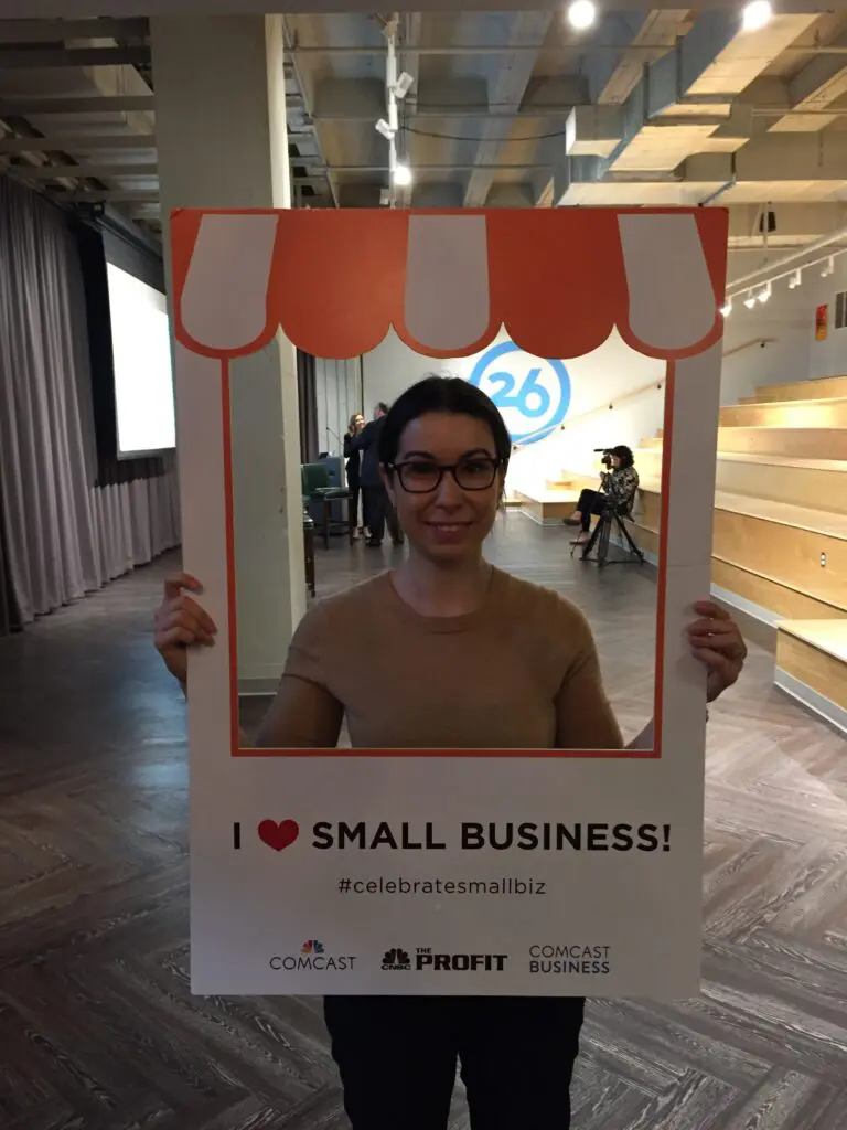 A woman holding up an "I heart small business" sign.