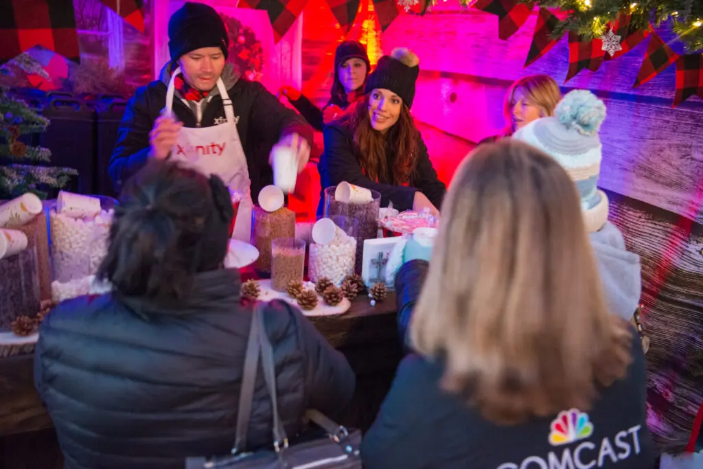 Xfinity volunteers serving treats to a line of people.