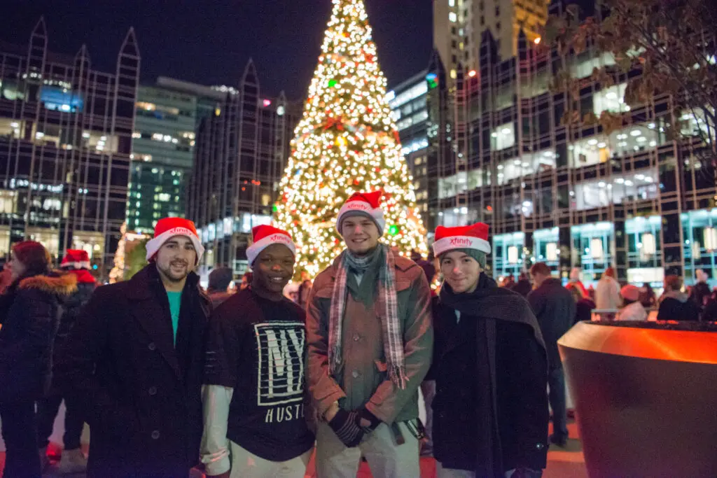 Four Xfinity team members standing in front of a Christmas tree.