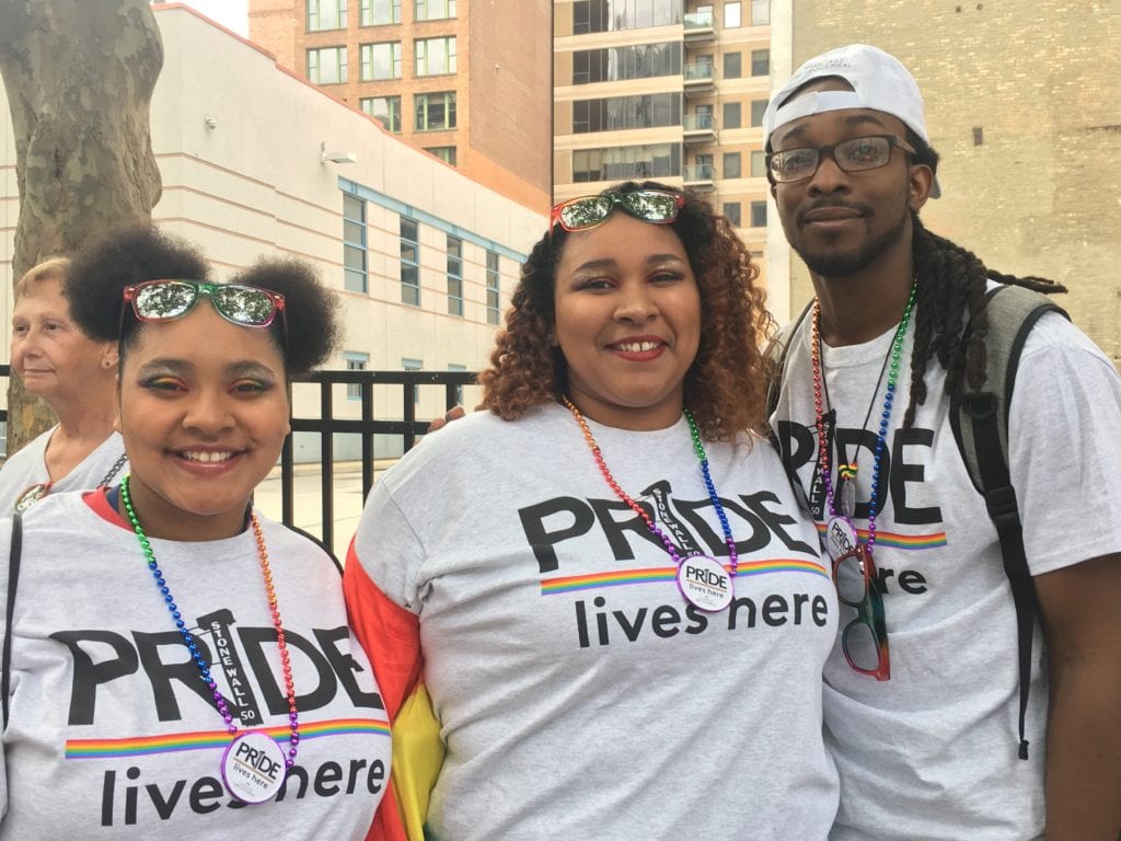 Three Comcast employees wearing shirts that say "Pride lives here."