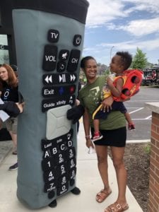 Person in an X1 remote costume talking to woman holding small boy