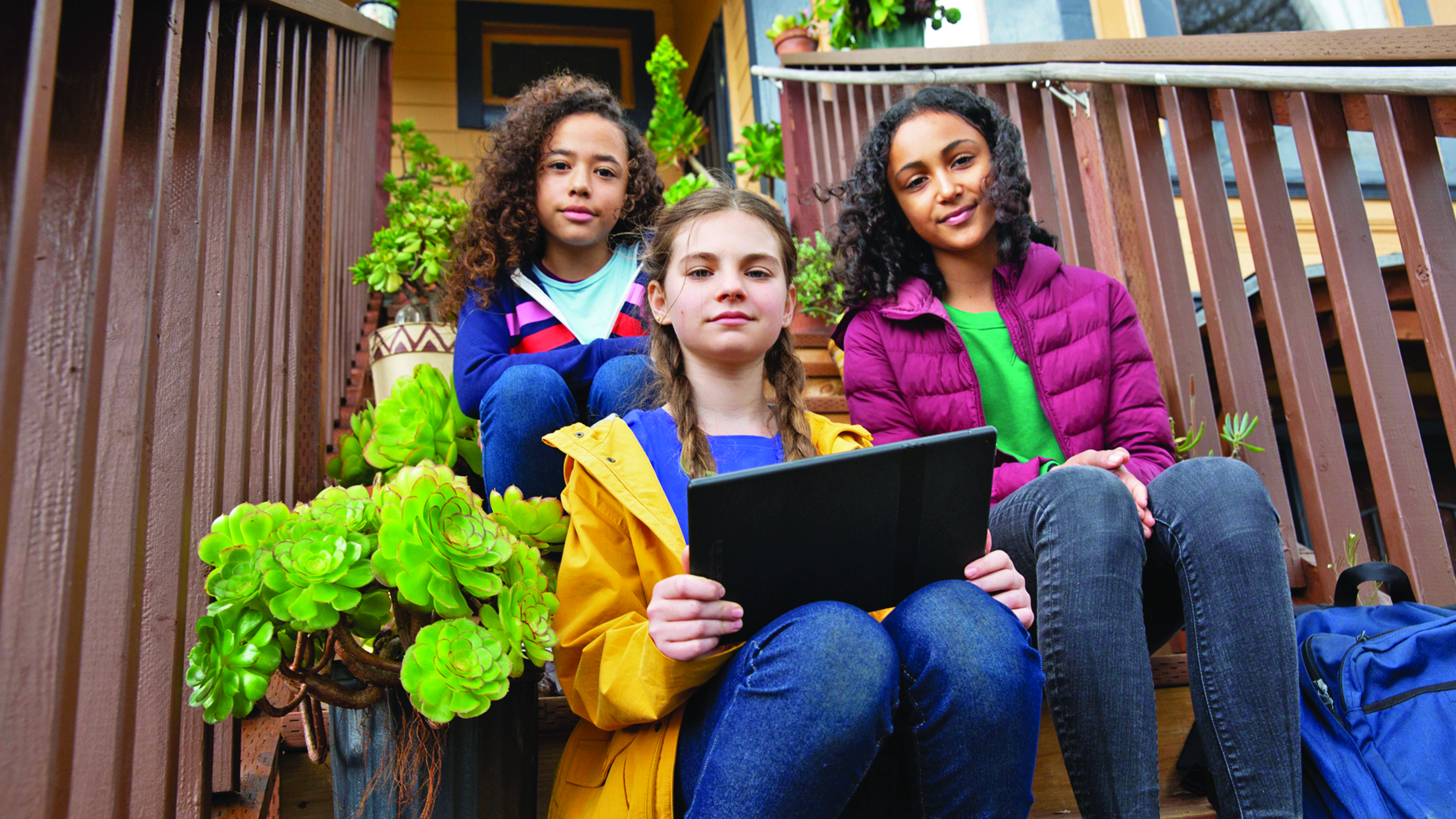 Three children sit together on a stoop.