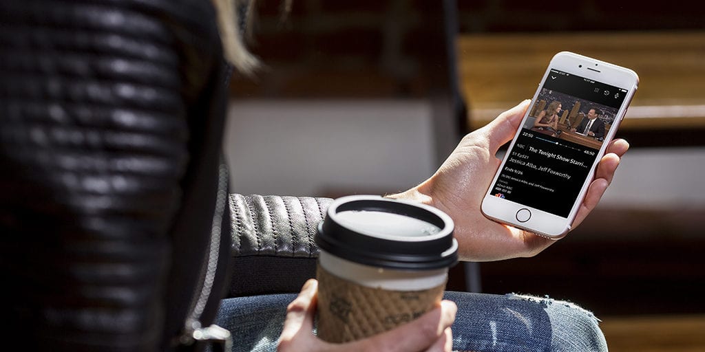 college student watching a movie from her smartphone while drinking a cup of coffee