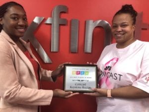 two women holding a plaque, standing in front of Xfinity logo