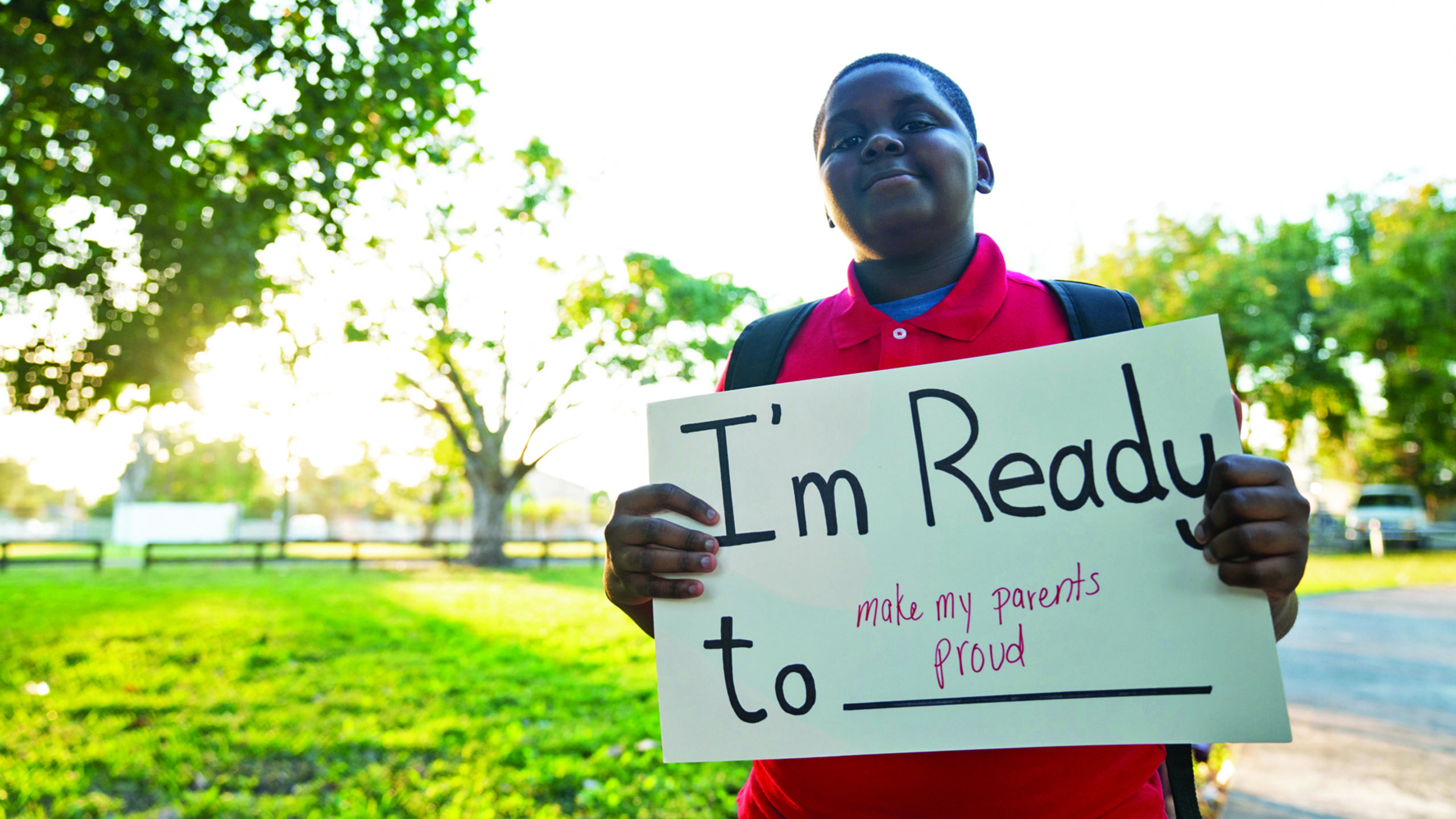 Boy holding sign that says "I'm ready to make my parents proud"