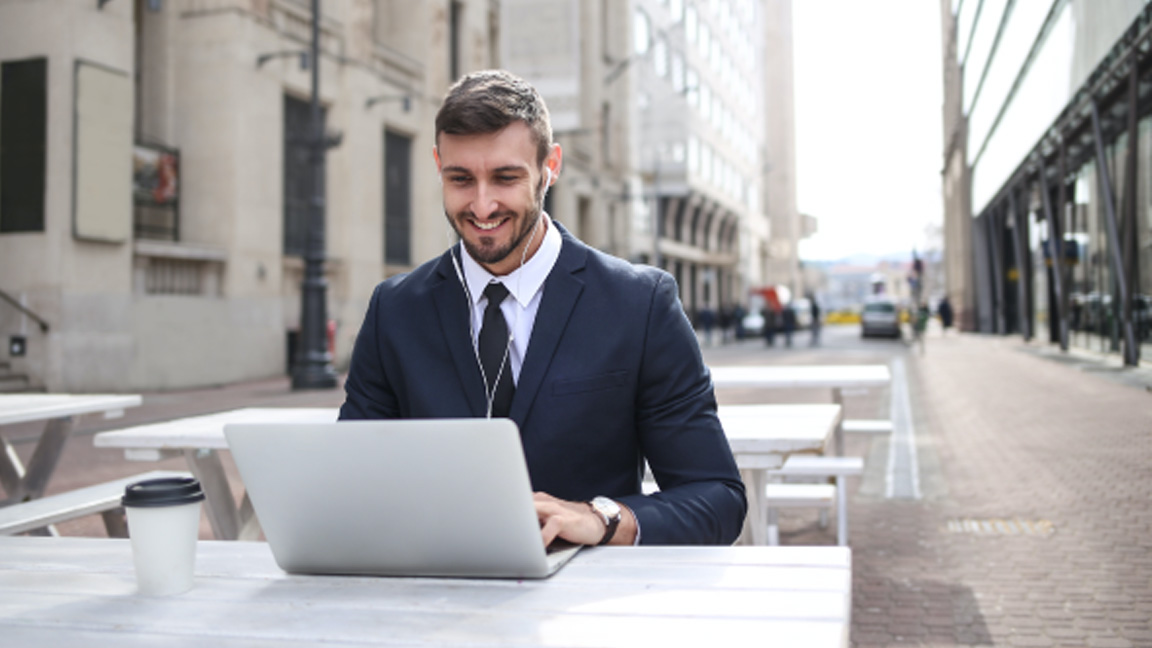 Man typing on a laptop outside