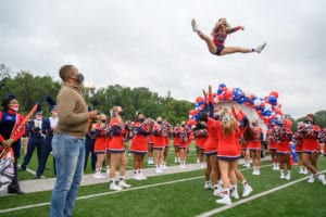 Cheerleader jumping as Craig Melvin watches