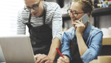 Two business owners working on laptop and using a phone