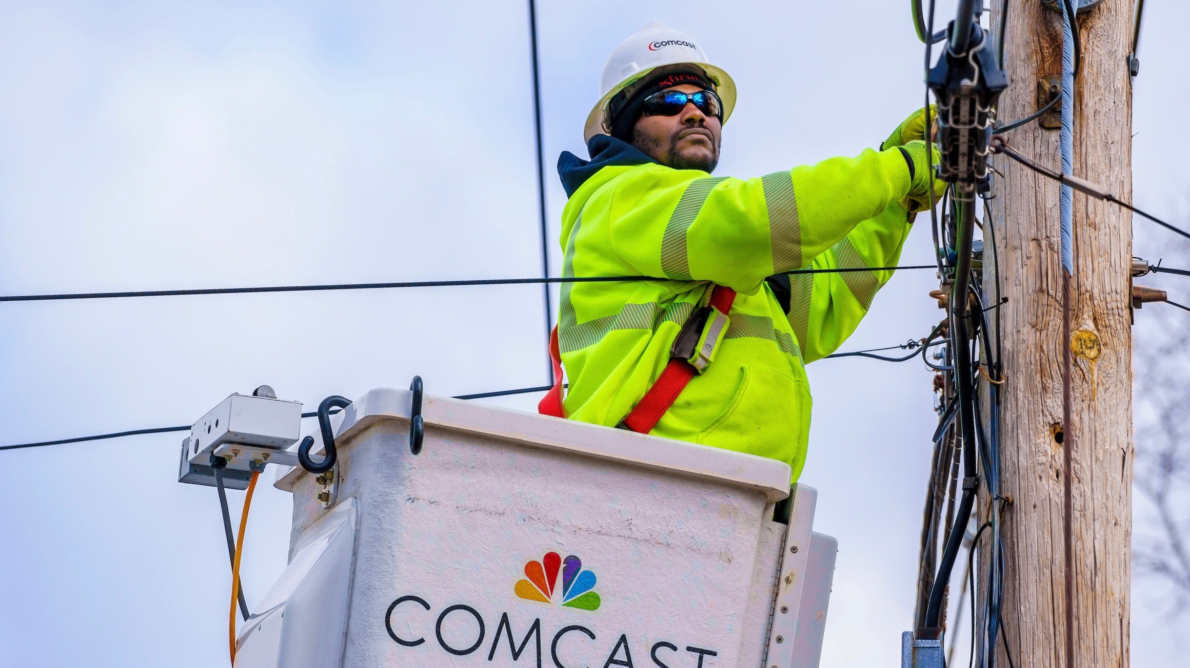 Comcast technician installing line on pole