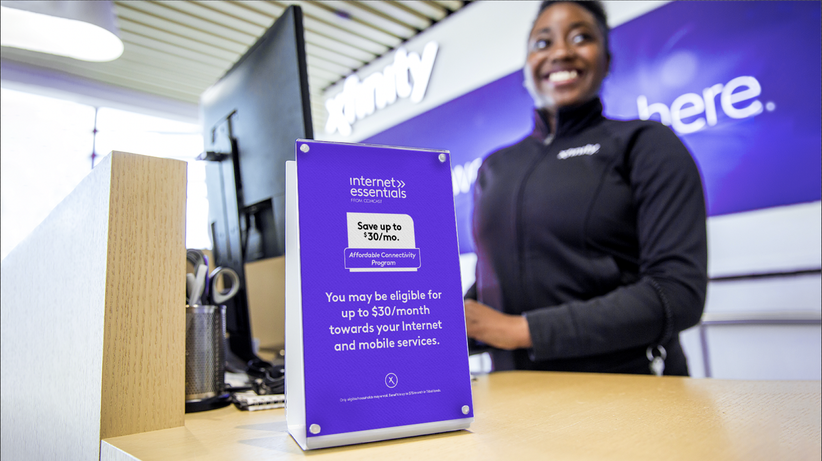 ACP sign in front of smiling Xfinity Store employee